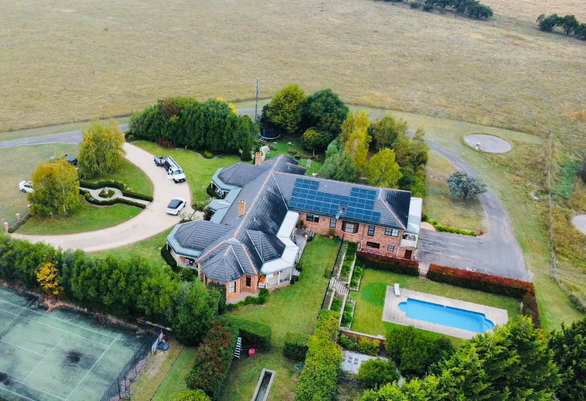 Aerial view of a country home with solar panels on its roof, installed by CES