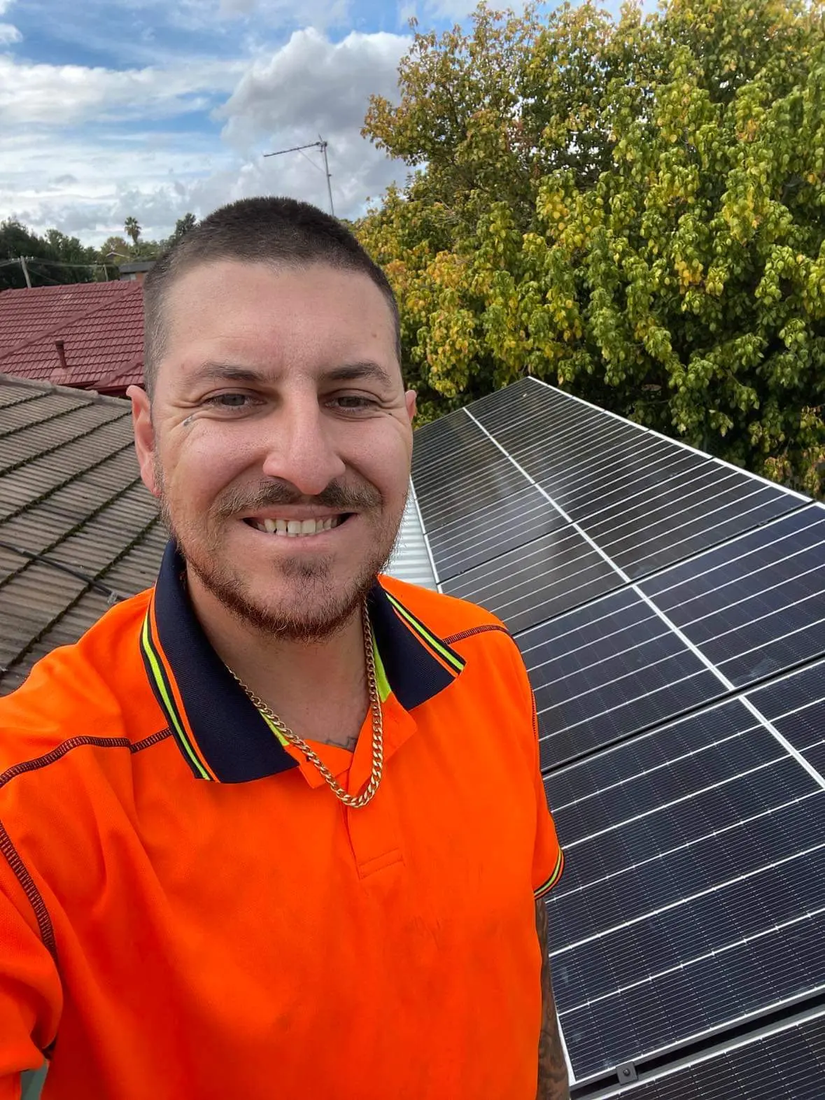 Daniel Grubisa in a hi-vis shirt on a roof beside newly installed solar panels