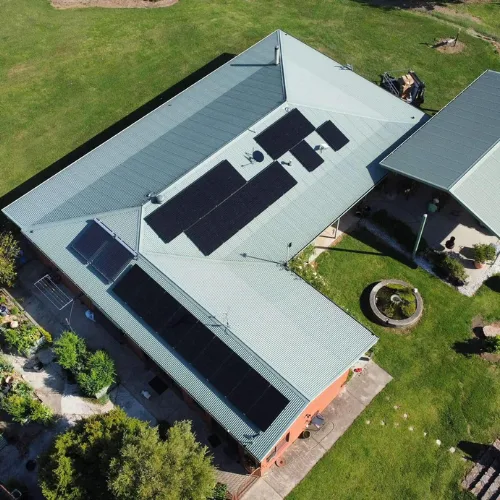 Drone view of a long Colorbond-roofed home on a lawn block with solar panels in three groups